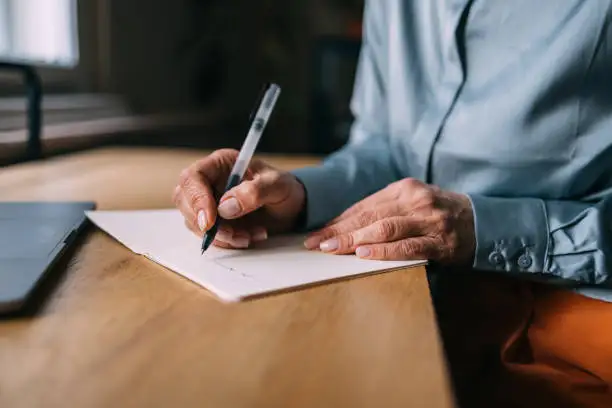 close up of a senior sitting at their desk writing on a piece of paper
