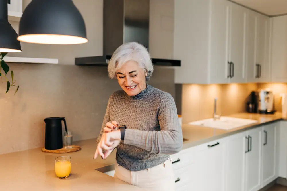 a senior woman checking her smartwatch while standing in her kitchen