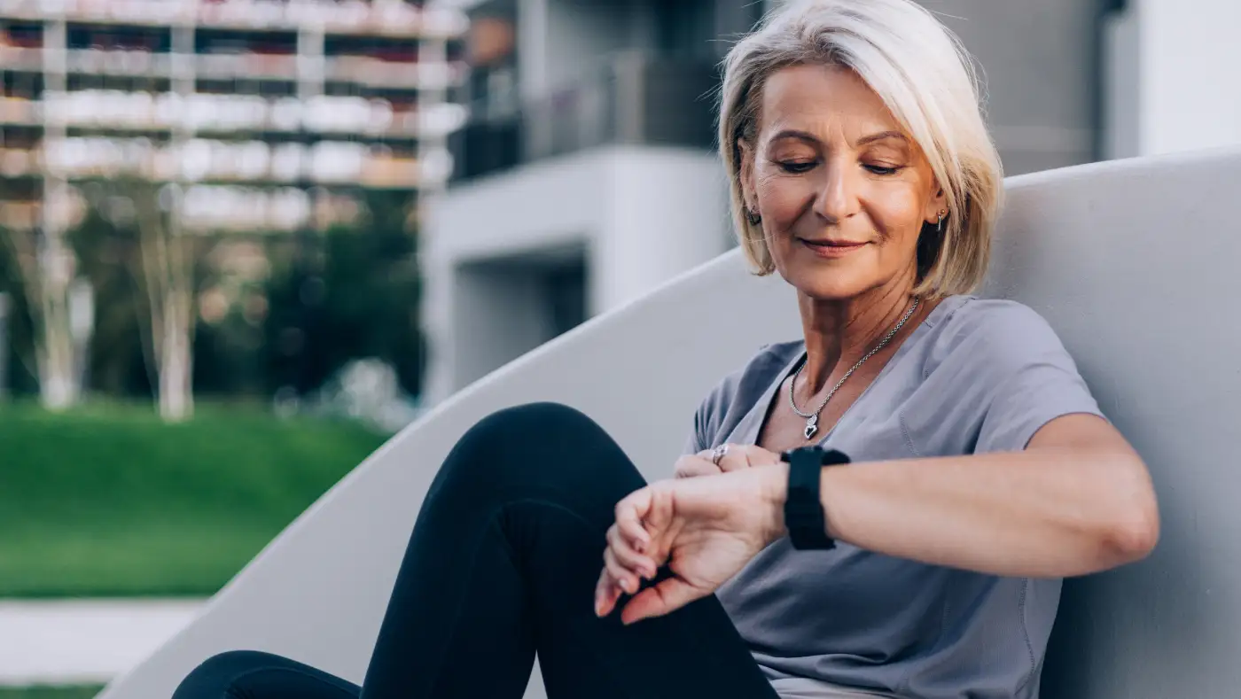 a senior woman checking her smartwatch while out for a jog