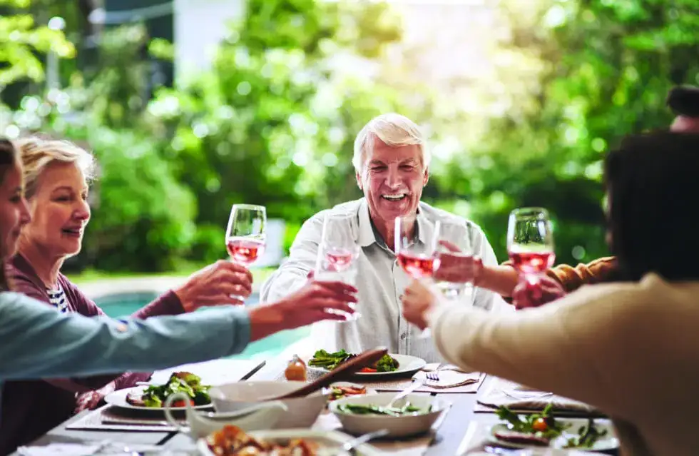 Cropped shot of a happy aged man making a toast with fellow members of the Winsberg during a lunch event outdoors