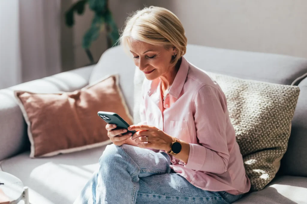 senior woman researching financial planning tips for seniors on her phone so she can retire at The Winsberg at Green Cay in Delray Beach, Florida.