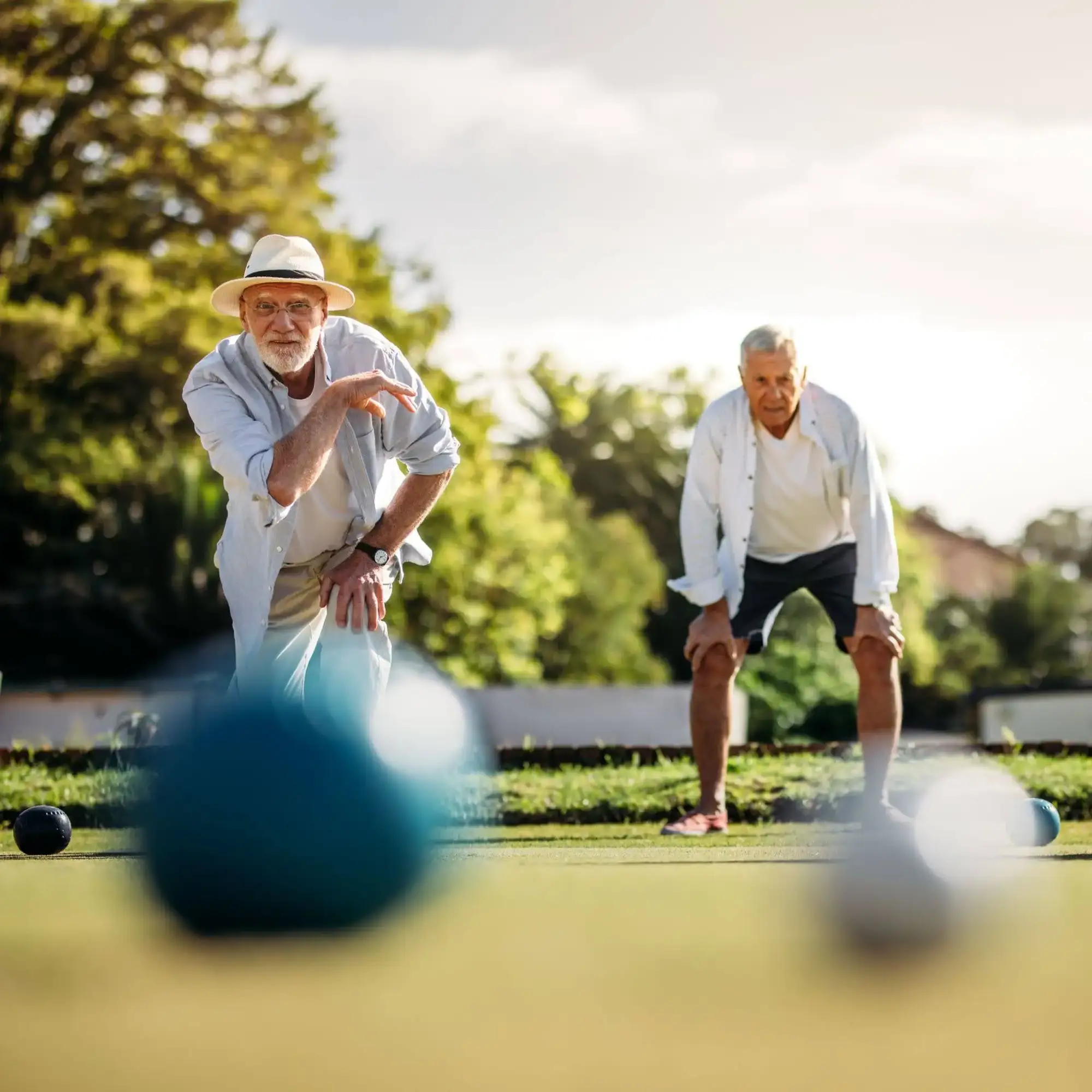 Two senior men playing bocce ball on the retirement campus resort at The Winsberg at Green Cay in Delray Beach, FL.